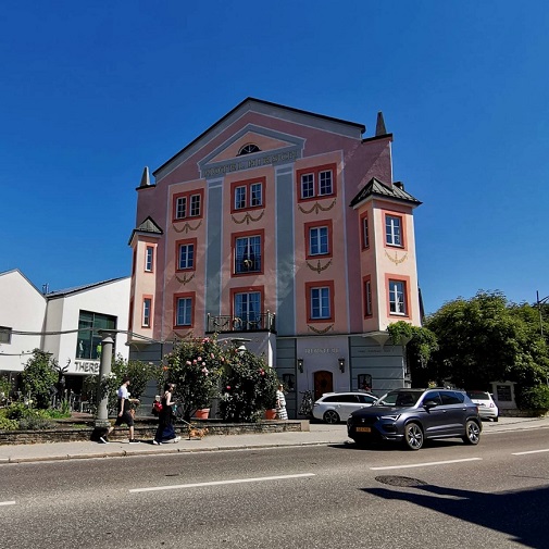 Straße, rosa Haus, Autos, Pflanzen, Fußgänger 