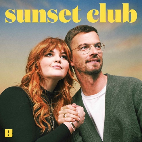 SunsetClub 2 Personen vor einem orange-blauen Hintergrund; in gelber großer Schrift steht: "sunset club"; die zwei Personen halten sich an den Händen und schauen nach vorne, links an der Kamera vorbei