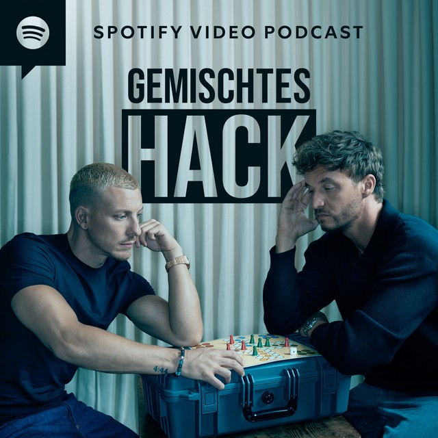 gemischtesHack Bild mit blaugrauem Unterton, heller, faltiger Vorhang im Hintergrund, 2 nachdenklich wirkende junge Männer sitzen im Fokus und stützen sich auf einem grauen Koffer ab. Auf dem Koffer steht ein "Mensch ärgere dich nicht-Spiel". In schwarzer großer Schrift steht oben "Spotify Video Podcast", darunter "Gemischtes Hack". In der oberen linken Ecke ist das Spotify Logo in schwarz zu sehen