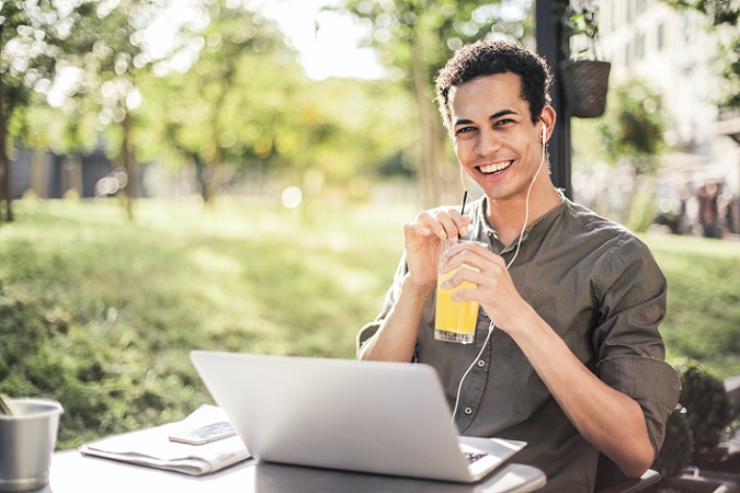 Jugendlicher mit einem Glas Limonade vor seinem Laptop